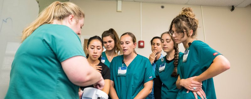 A group of Virginia Tech MSND students stand together in a group to observe a demonstration by a Carilion Clinic Registered Dietitian