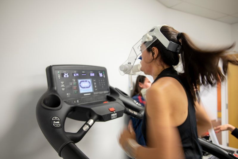 A person running on a treadmill wearing a cap to track brain activity.