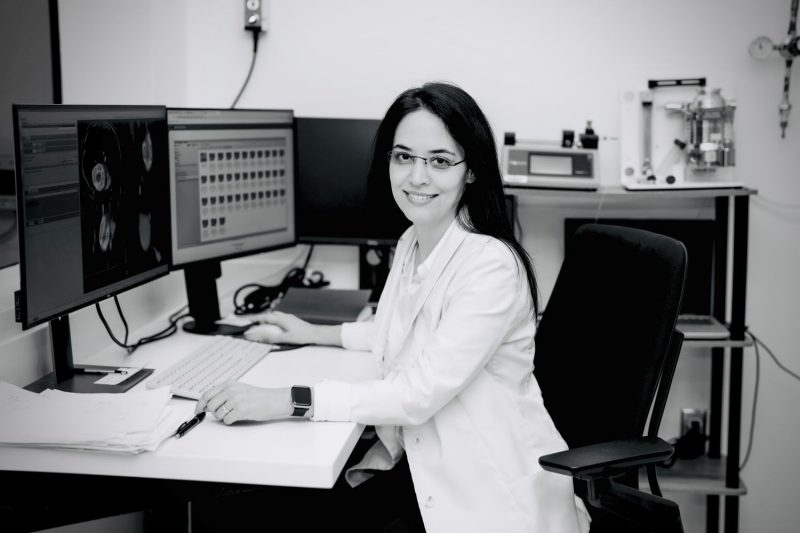 A professor sits a desk with three desktop monitors.