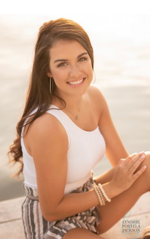 A Virginia Tech HNFE Ambassador sits on the beach for a photo.